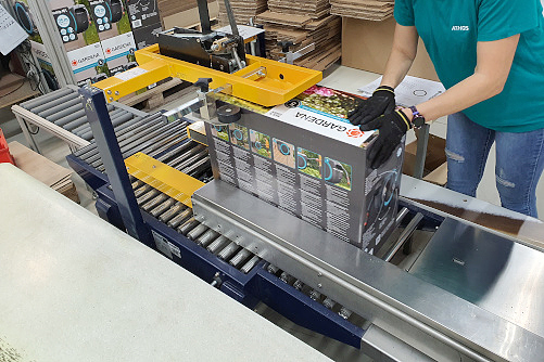 Employee packing a hose rewinder in a cardboard box